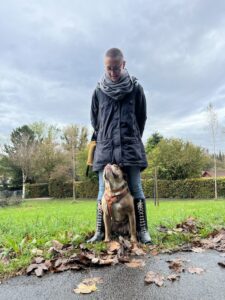 Einzeltraining: eine Frau steht breitbeinig da, ihr Hund sitzt zwischen ihren Beinen und schaut zu ihr hoch